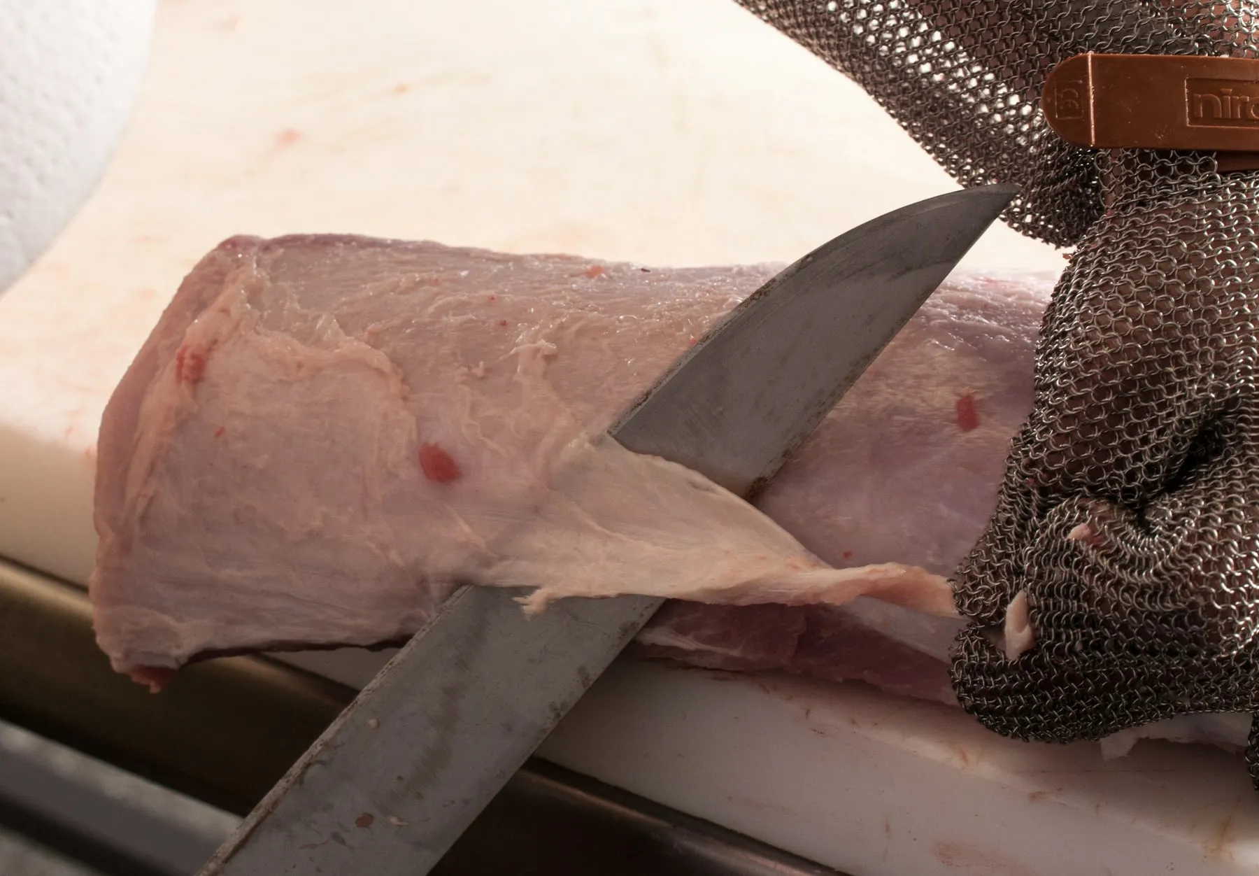Carnicero cortando carne con cuchillo sobre la mesada