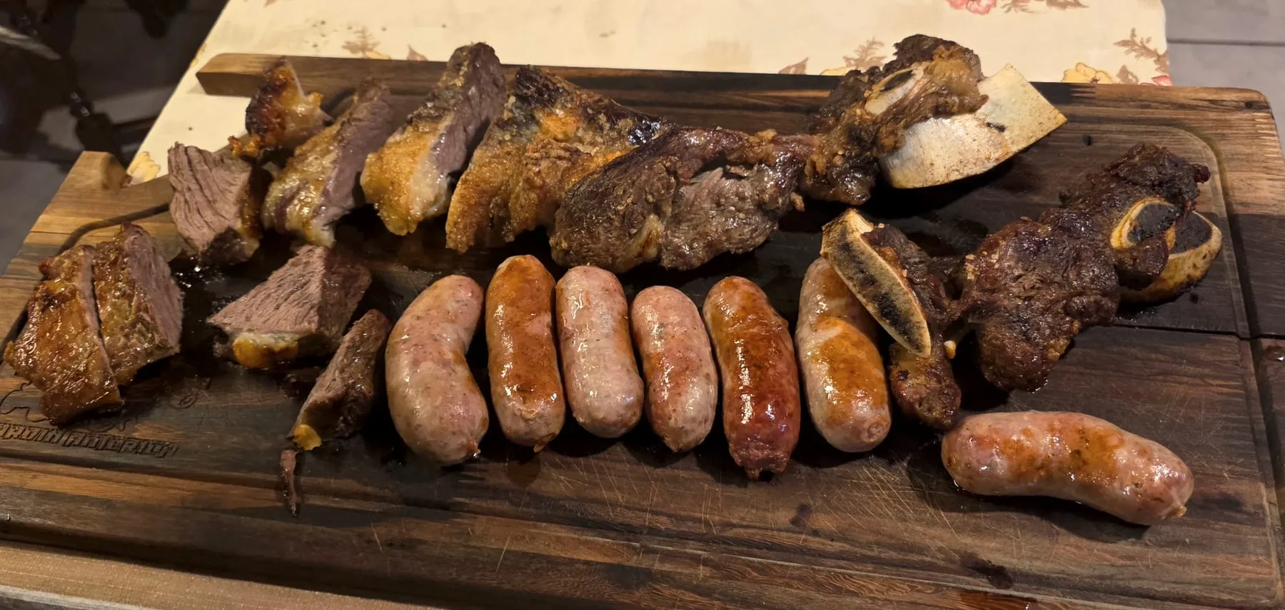 Tabla de asado con chorizos, costillas y cortes de vaca recién salidos de la parrilla